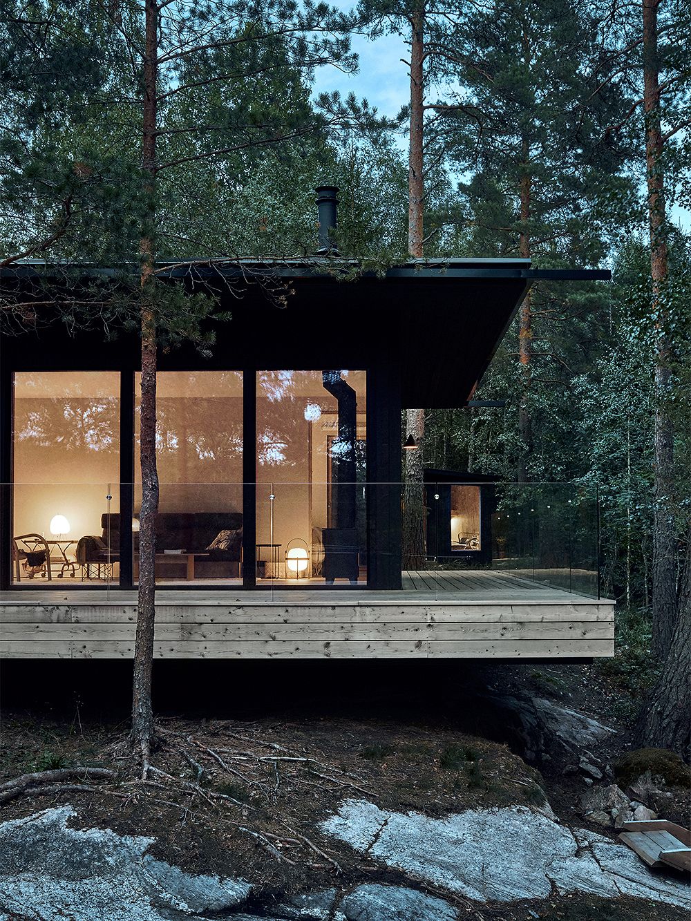Modern vacation home surrounded by trees, built on a rocky hill