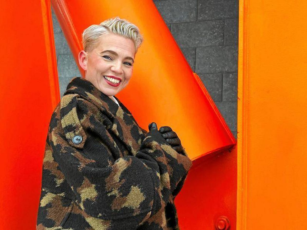 Helsinki Pride -yhteisön toiminnanjohtaja Annu Kemppainen kuvattuna oranssia taustaa vasten